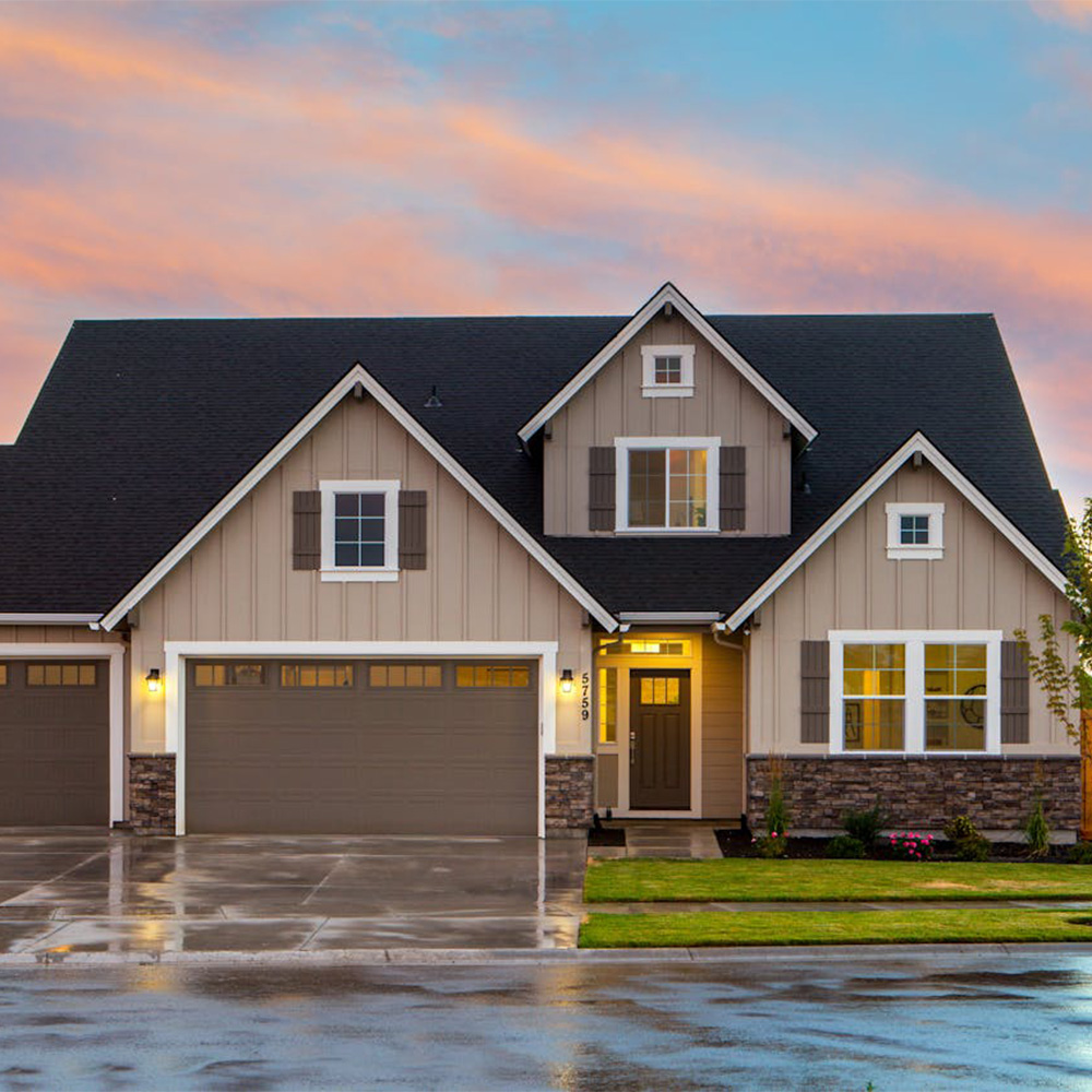 Two-story house with an attached garage and illuminated windows at dusk